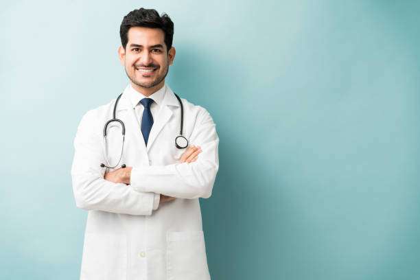 Smiling Hispanic doctor standing with arms crossed against blue background
